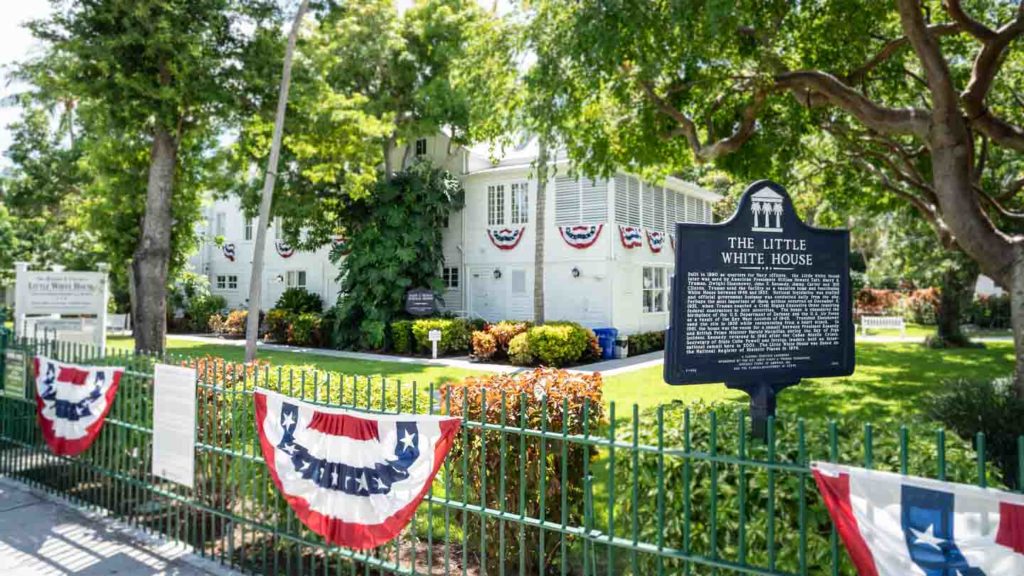 View of the grounds and the large white exterior of the Harry S Truman Little Whitehouse in Key West